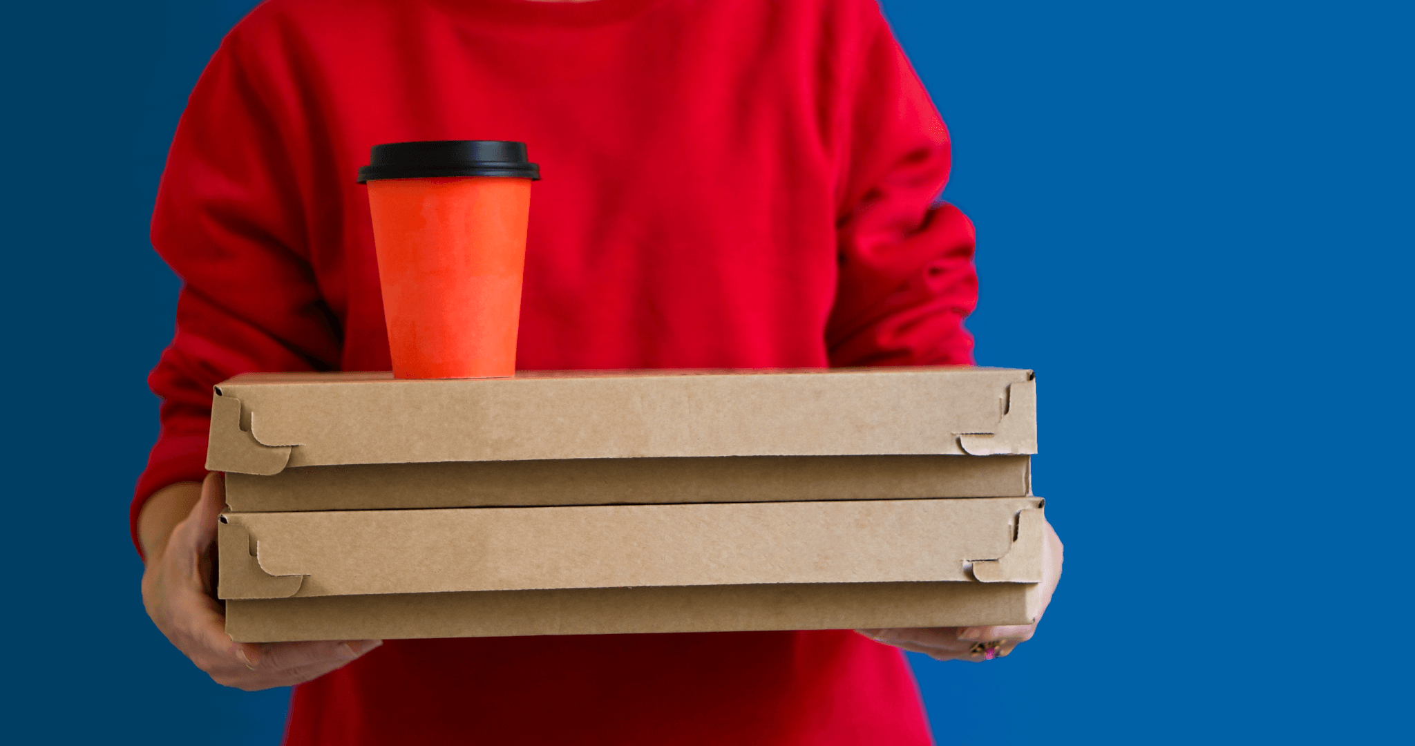 staff member holding two pizza boxes and a hot drink