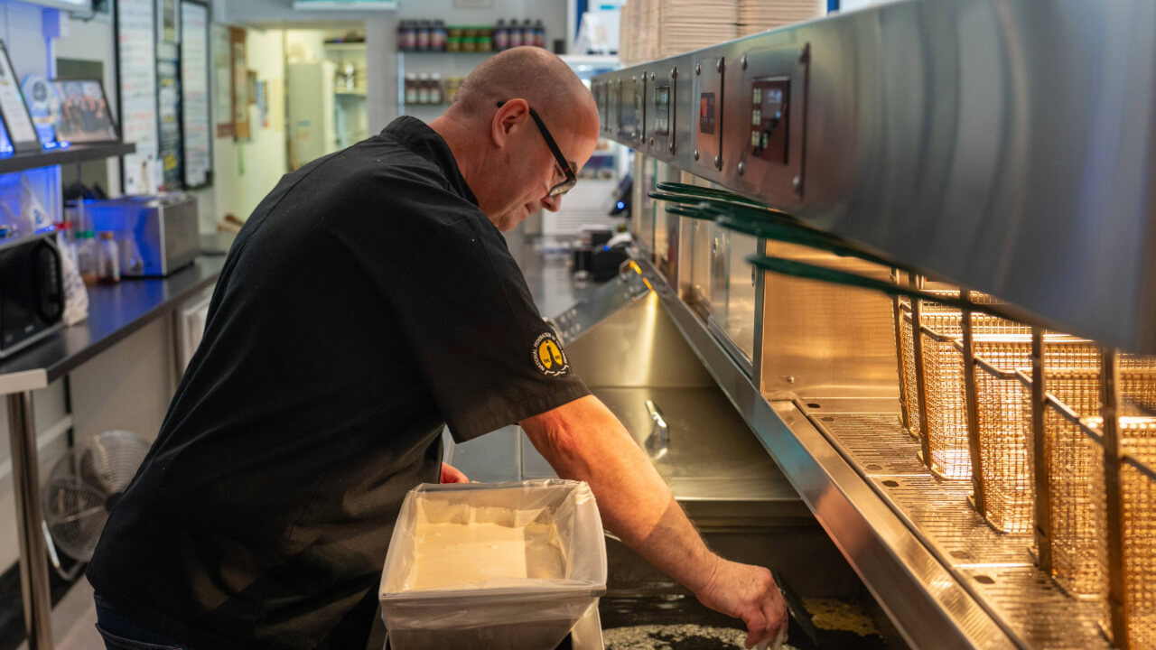 Adding laying battered fish in the fryer.